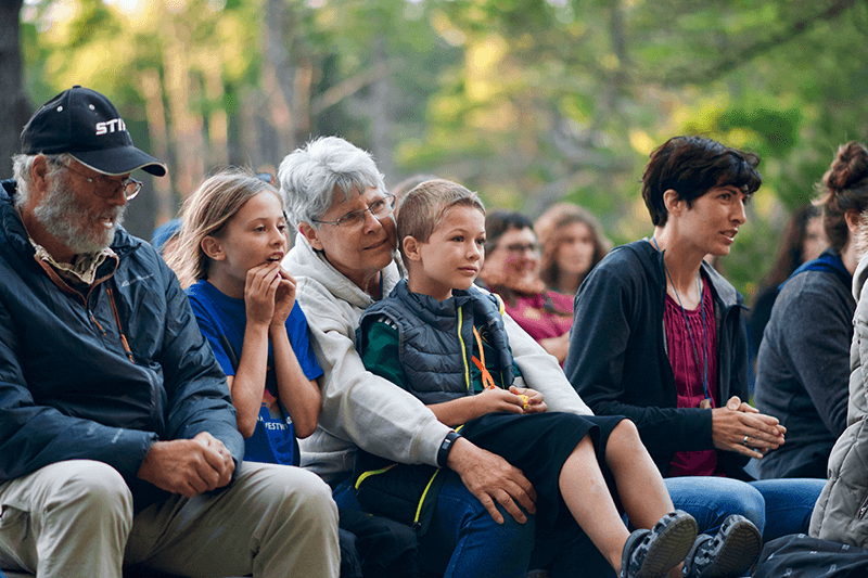 Family with kids sat watching at camp