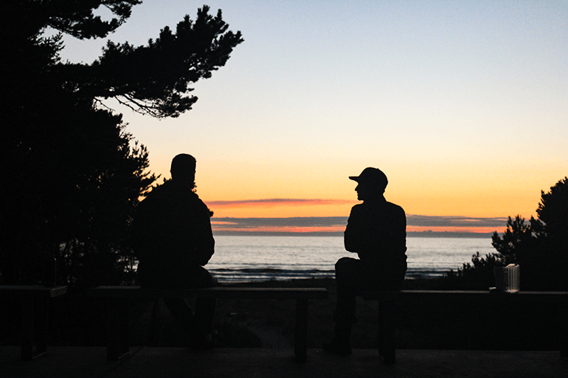 Two campers enjoying a beautiful sunset over the water