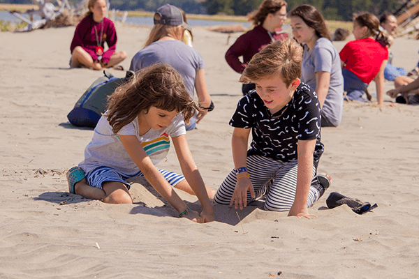 Two young children playing in the sand on the beach at camp westwind