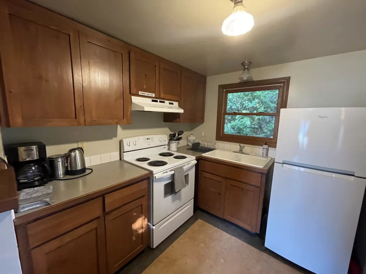 Kitchen with refridgerator, stove and wooden cabinets.