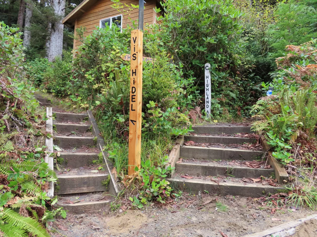 Two wooden sign post with directions, wooden stairs leading to left and right.