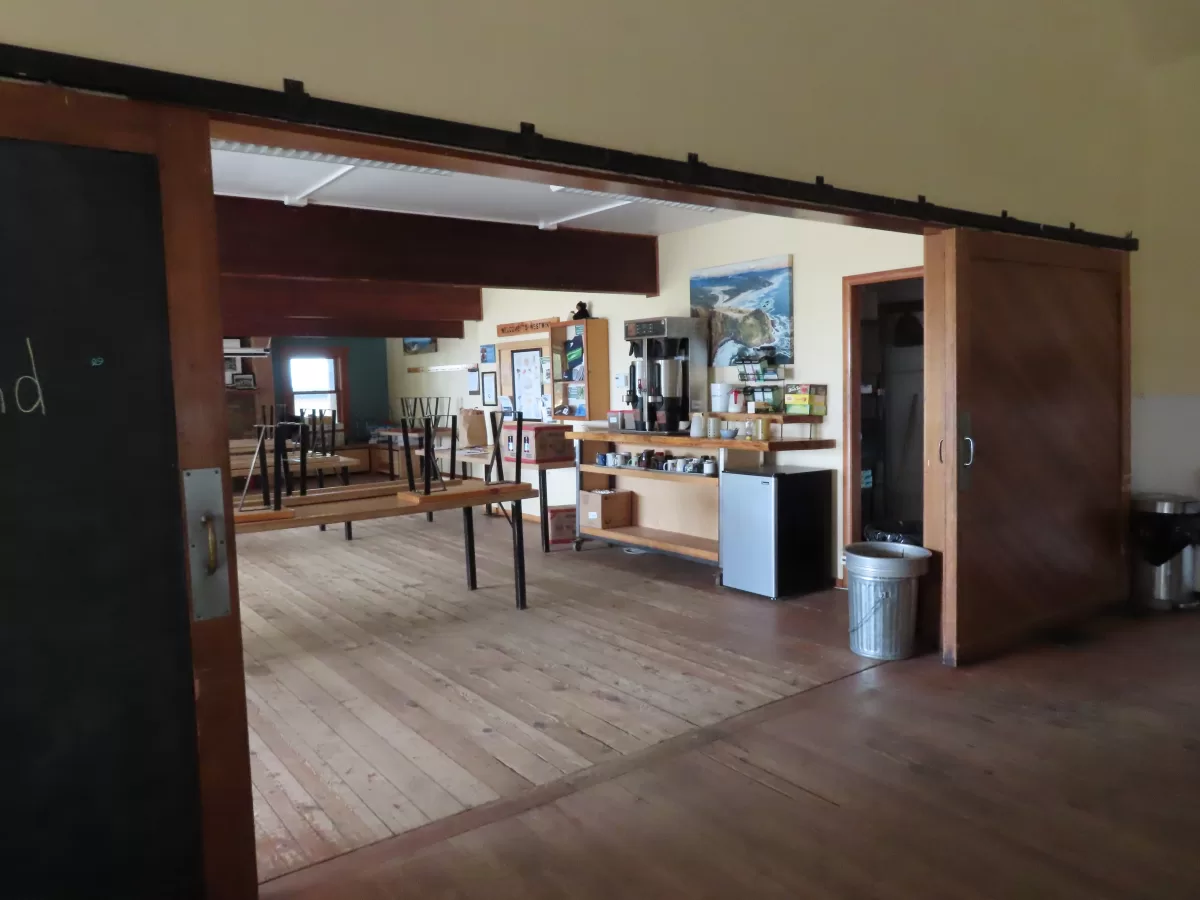 Interior lodge with tables and benches, coffee bar and supply closet.