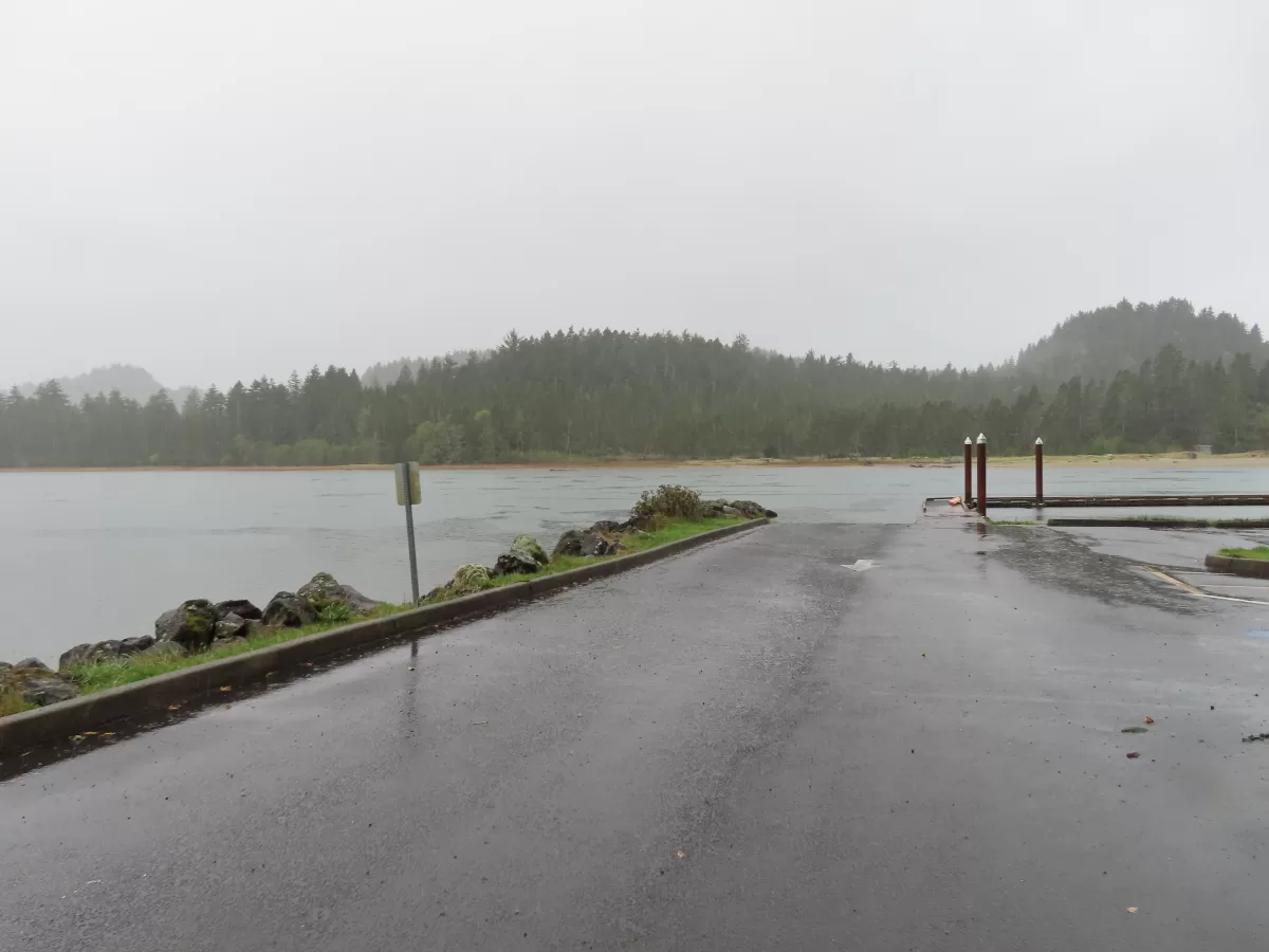 Pathed parking lot leading to boat ramp. Floating dock on river. Westwind beach on other side of river.