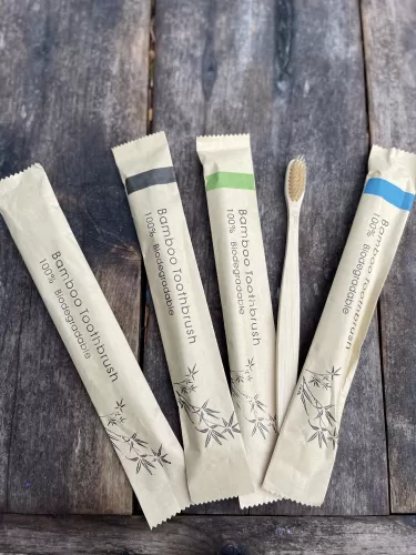 Four paper wrapped bamboo tooth brushes, one unwrapped