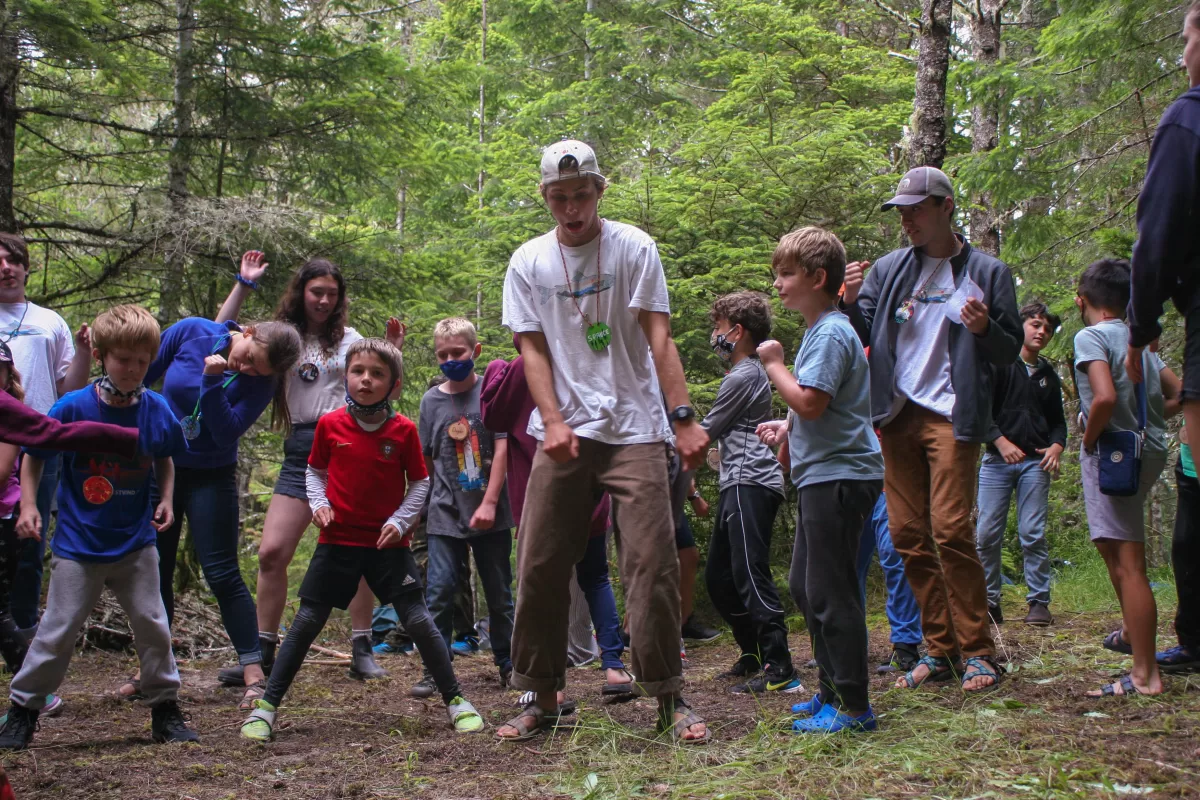 group of young campers dancing in the woods
