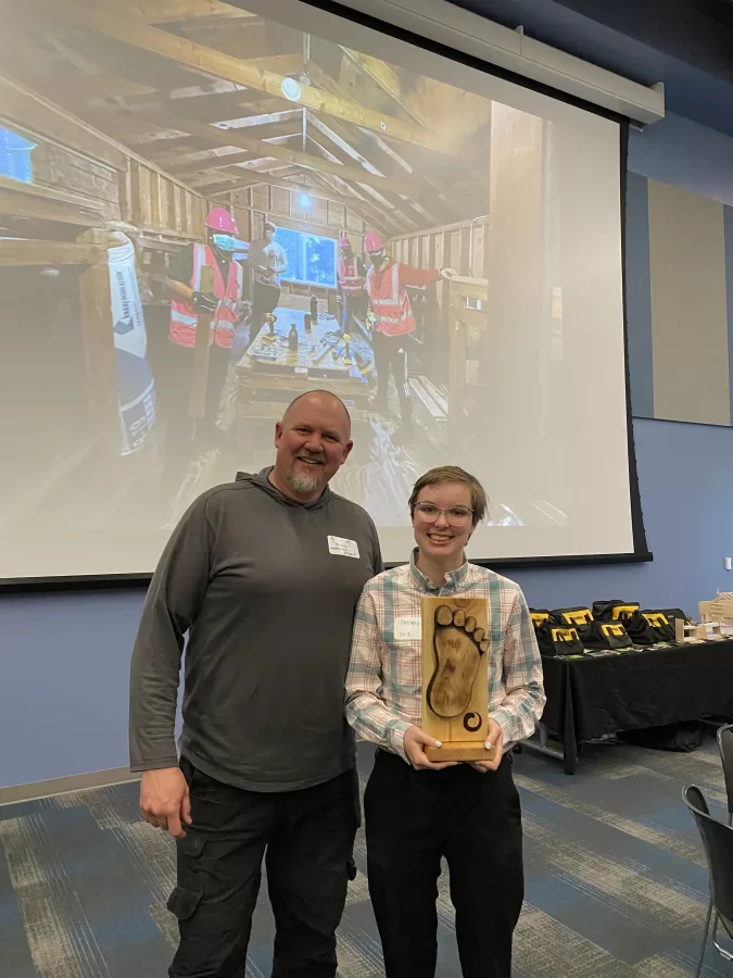 man and teen pose for photo holding wooden award