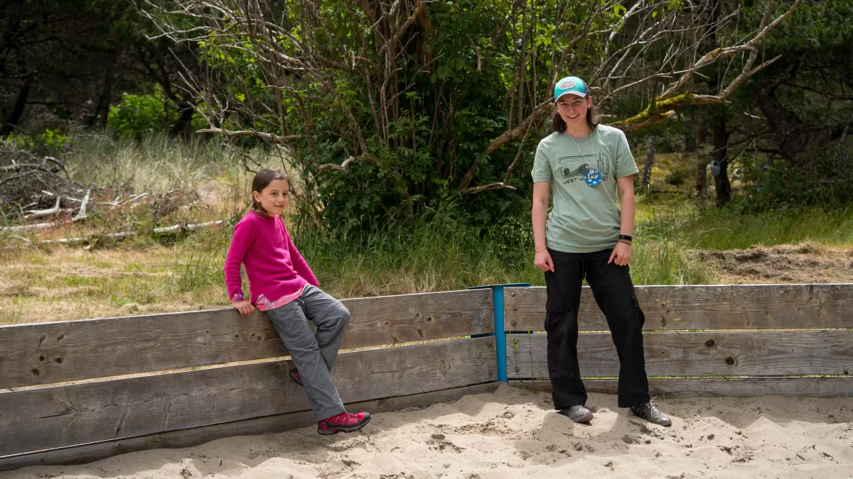 camper and staff member sit on a wooden railing