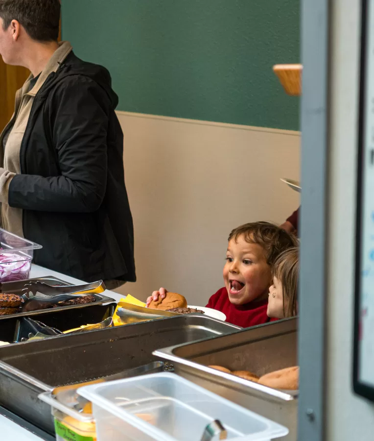 child smiles at plate with hamburger