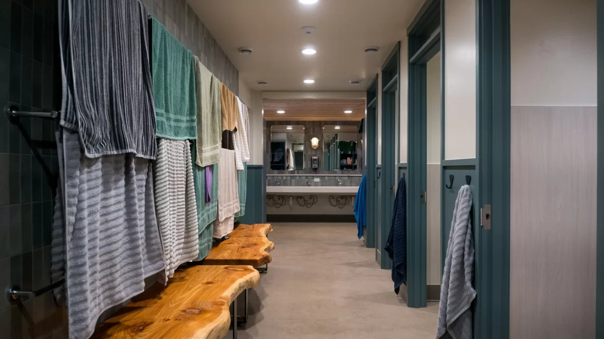 bathroom hallway with benches and toilet stalls.