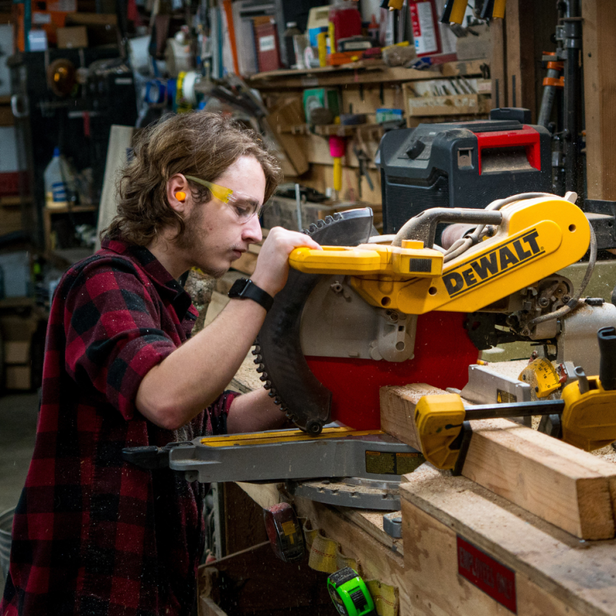 A man cuts wood with a power saw. 