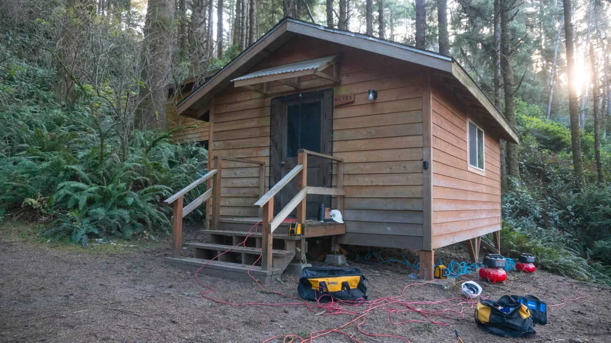 a wooden cabin with power tools on the ground in front