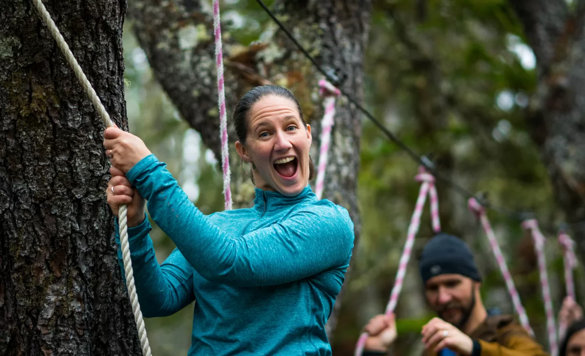 a woman holds on to ropes while smiling at the camera