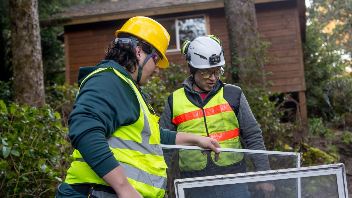 Student and teacher wearing safety vests move windows.